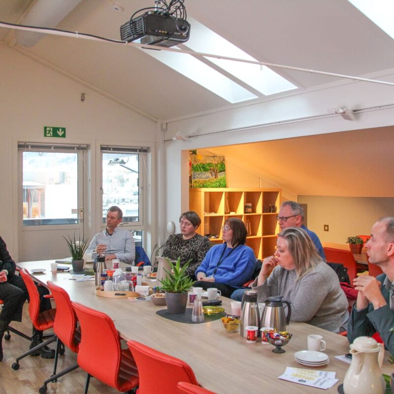 bilete viser sju personar som sit rundt eit bord i frokostmøte