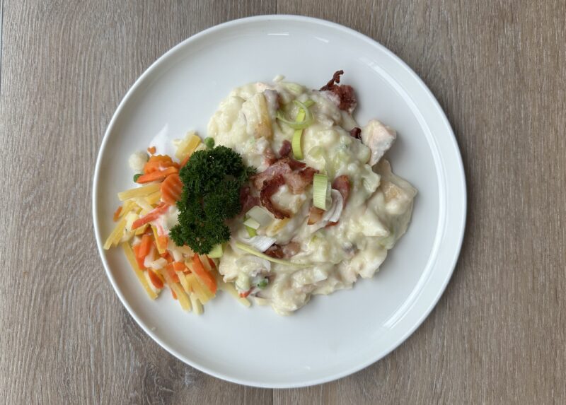 Bilete visar eit kvit fat med plukkfisk med strimla grønsaker, pyntet med persilledusk og purreløk.