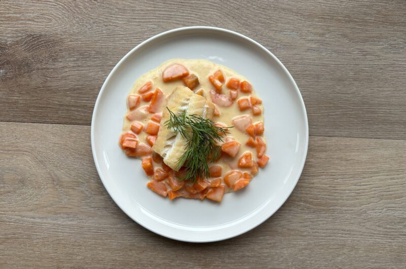 Bilete visar eit kvit fat med røykt torsk og gulrotpurre pyntet med dill.