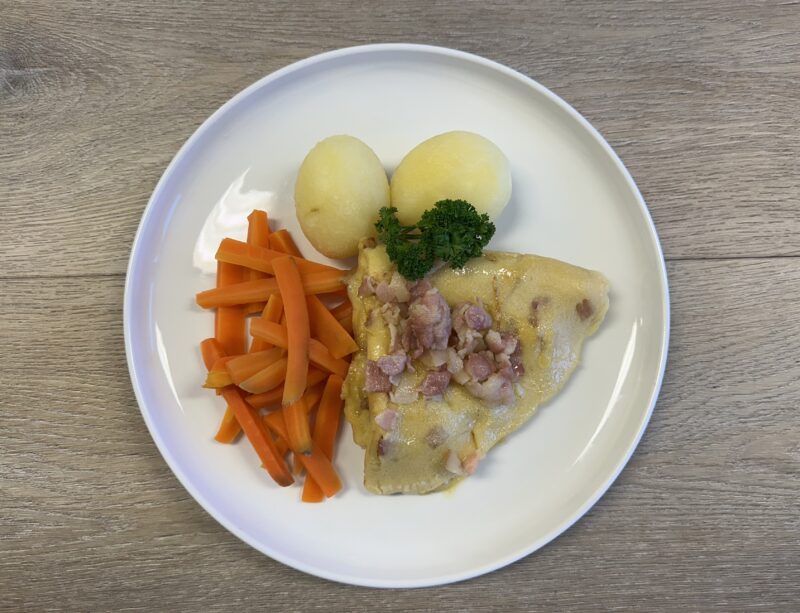 Bilete visar eit kvit fat med fleskepannekake, gulrot, potet og persilledusk