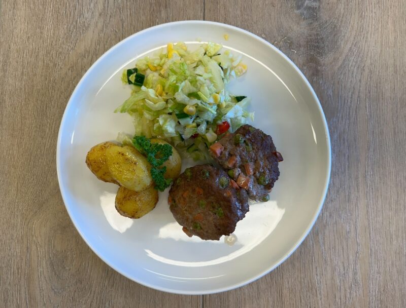 Bilete visar kvit fat med lunjskaker, salat og stekt potet pyntet med persilledusk.