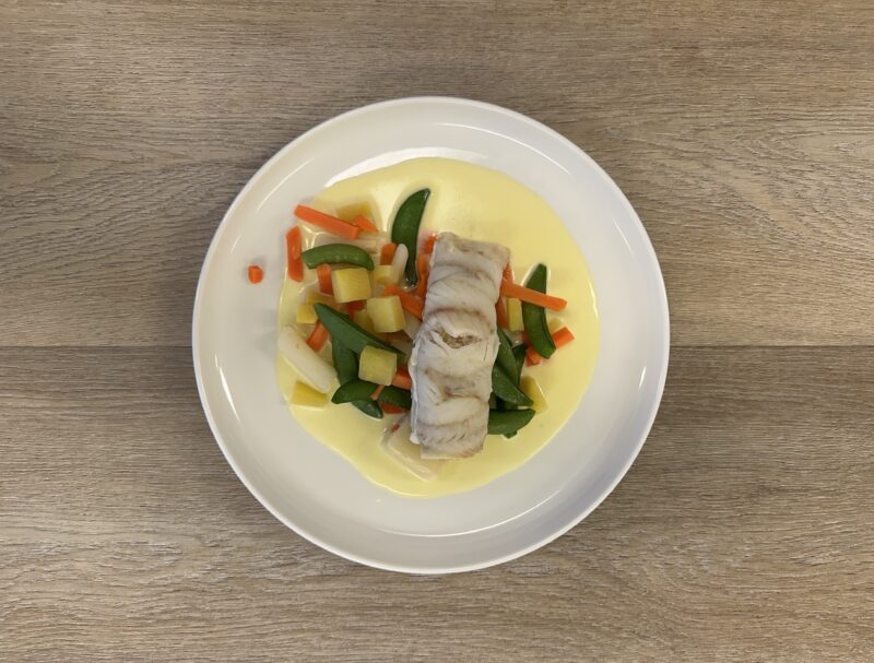 Bilete visar eit kvit fat med fiskerullade, grønsaker og saus.