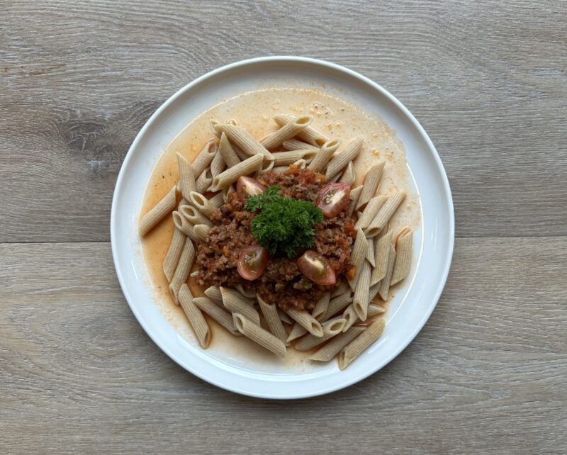 Bilete visar kvit fat med pasta og tomatsaus m/kjøttdeig ,pyntet med tomater og persilledusk.