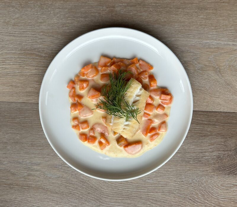 Bilete visar eit kvit fat med røykt torsk og gulrotpurre pyntet med dill.