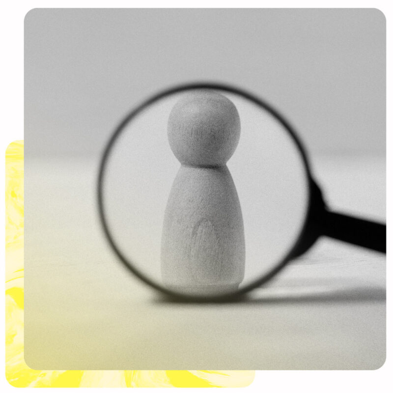 Et bilde av et forstørrelsesglass mot en liten trefigurer av et menneske skal symbolisere rekruttering. Bildet er i sort og hvitt, og bak er en gul dekorativ kant.